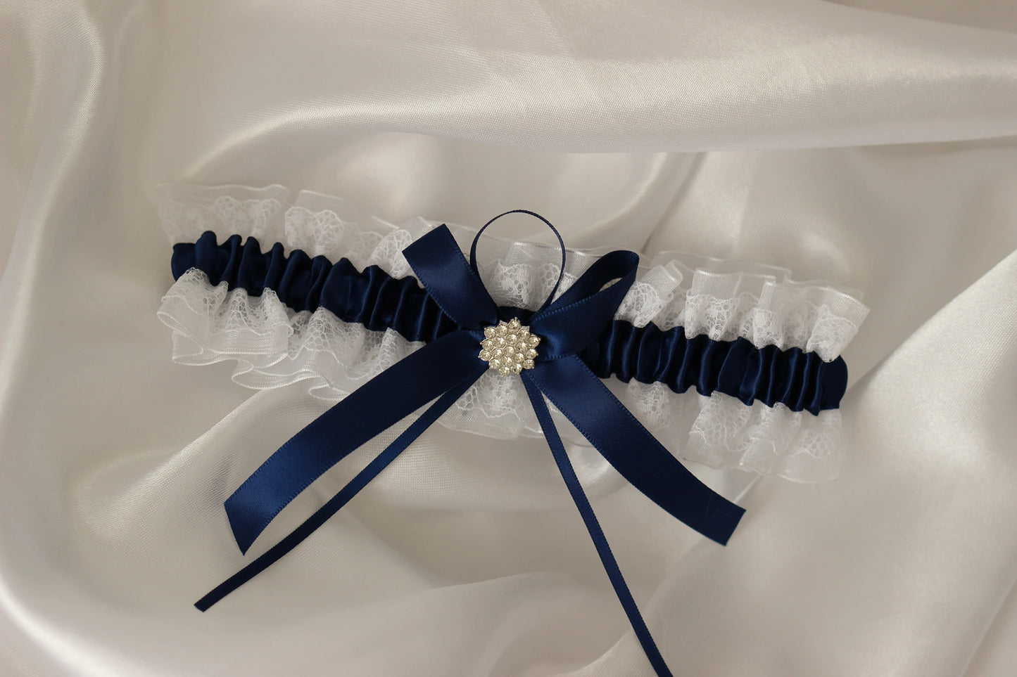 Navy blue lace bridal garter on white satin background