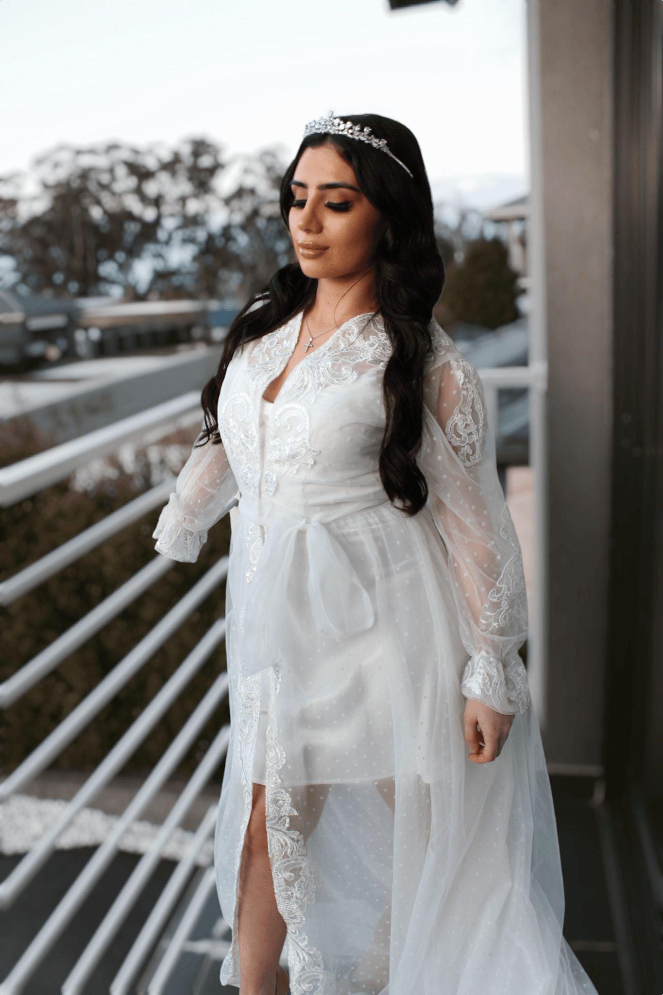 Bride wearing the Ariana Lace Robe with lace accents and poke dot details, posing gracefully on a balcony.