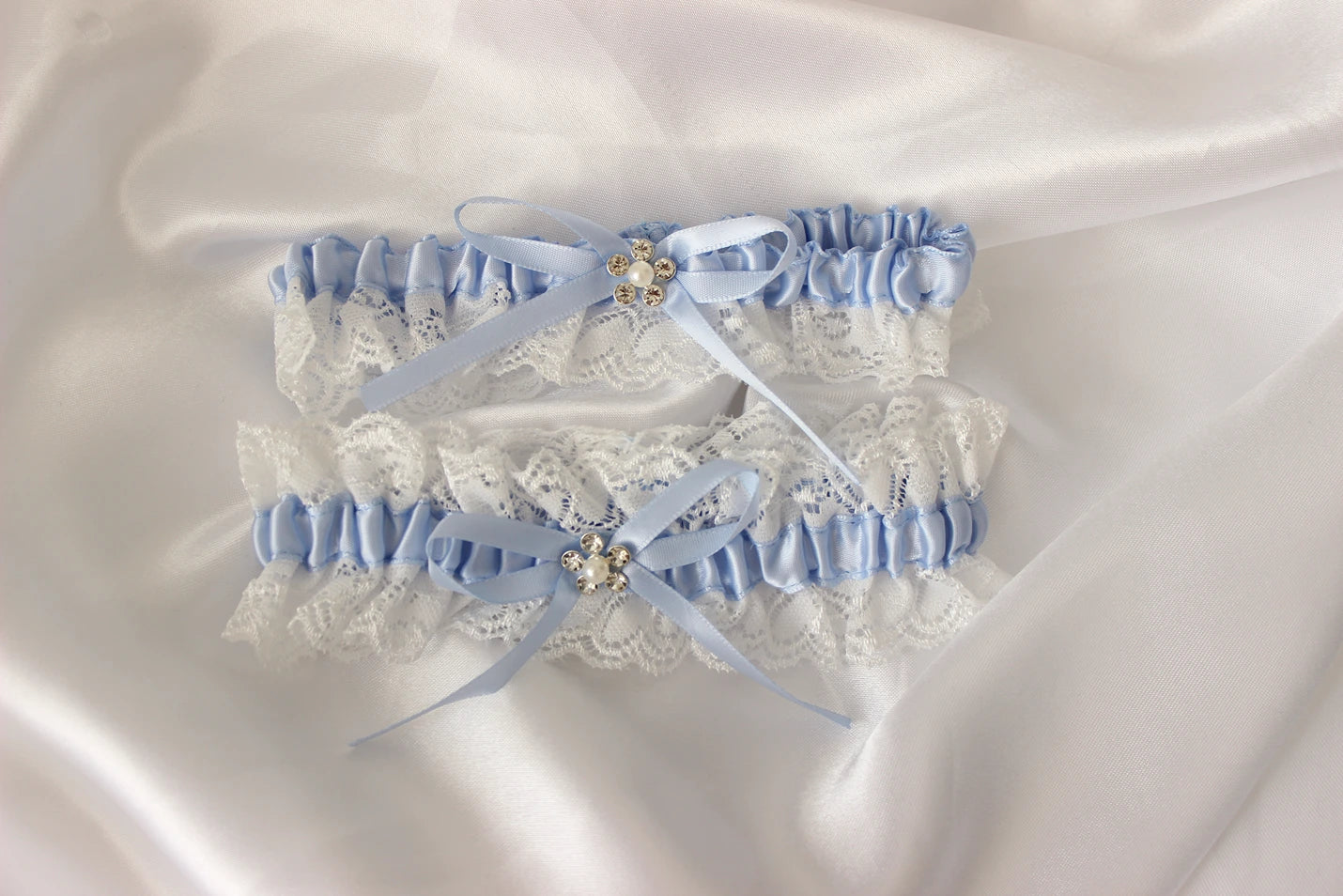 Pair of lace garters with blue ribbons on a satin background