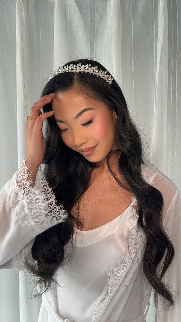 bride wearing lace robe whilst touching tiara