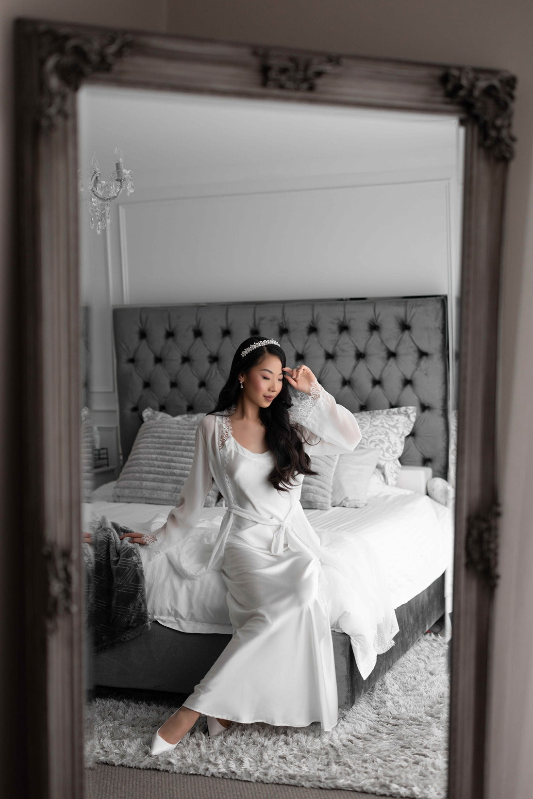 Bride wearing lace trim bridal robe with bridal tiara on bed