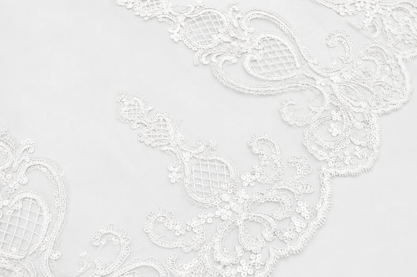 White floral lace trim with intricate embroidered patterns and scalloped edges, shown in a close-up detail view.