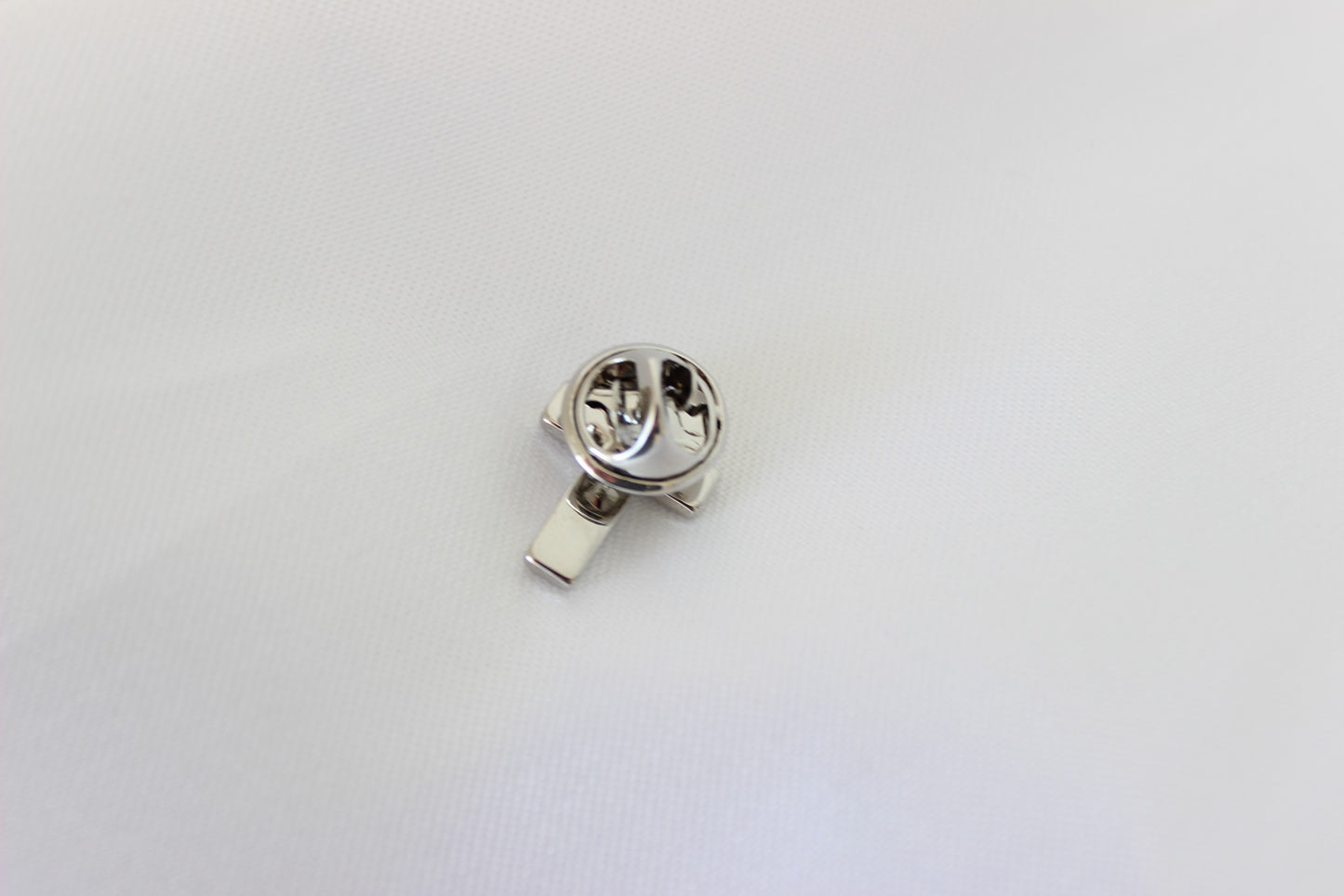 Black and silver cross pin worn on men’s suit lapel