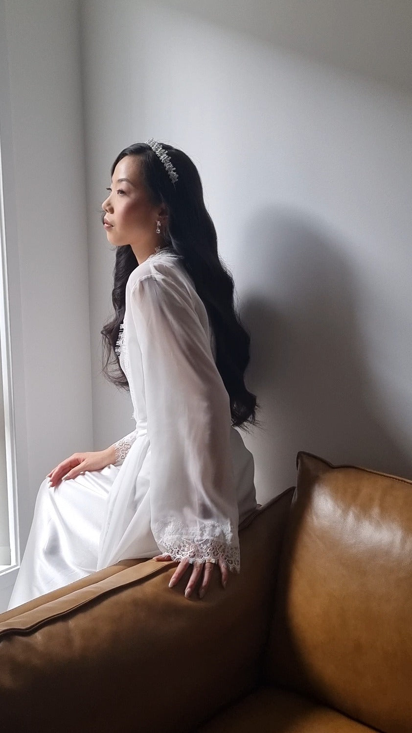 Model wearing lace bridal robe sitting on brown couch