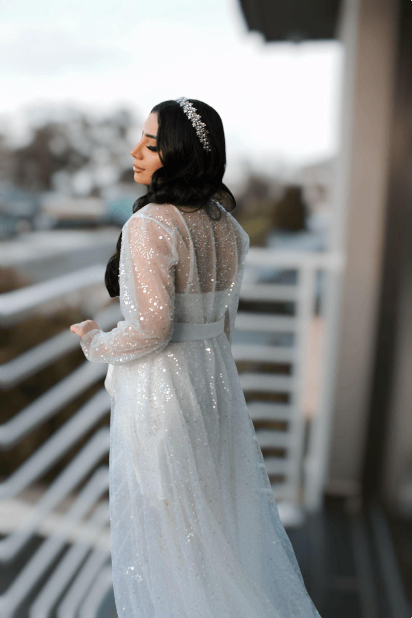 Bride wearing the Veronique Sequins Bridal Robe, looking back over her shoulder, with sequins sparkling in the light.