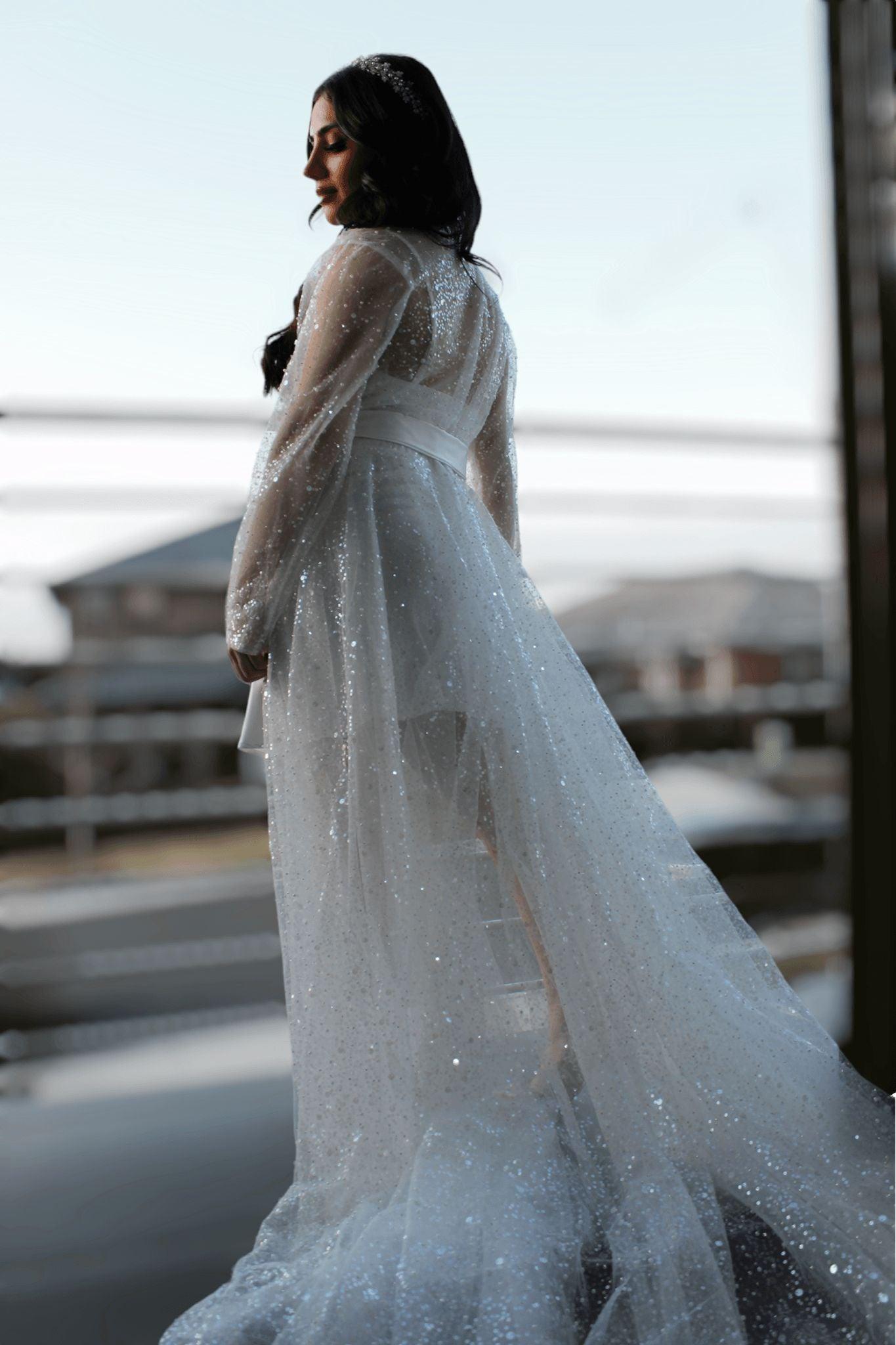 Bride wearing the Veronique Sequins Bridal Robe, standing sideways on a balcony, looking down gracefully