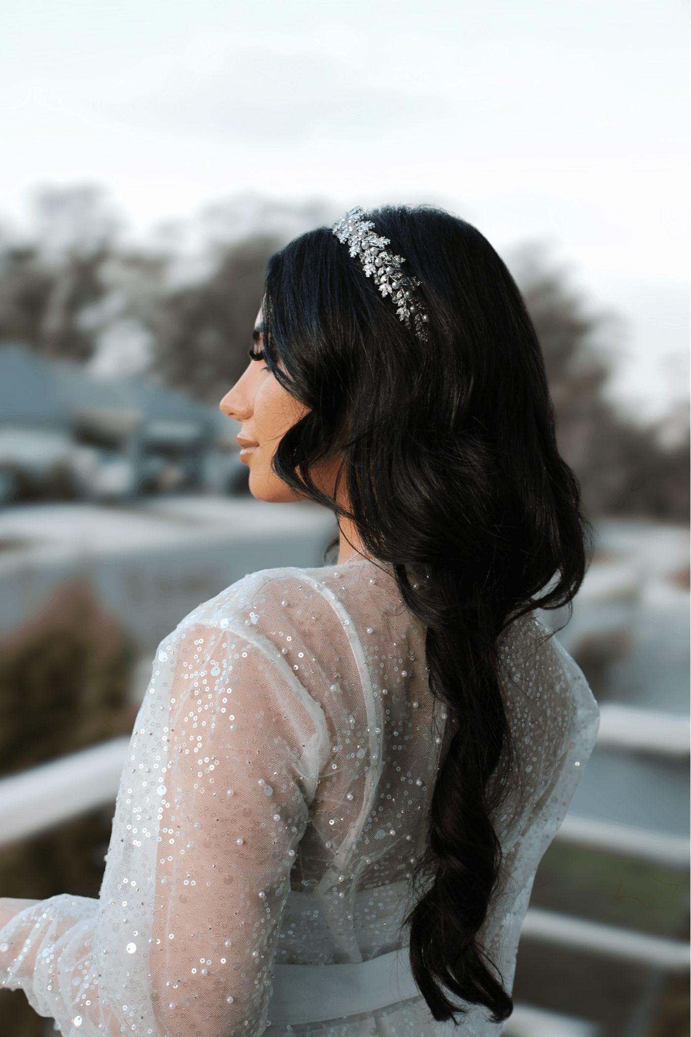 Close-up of bride wearing the Veronique Sequins Bridal Robe, leaning over a balcony railing with sequins sparkling in natural light