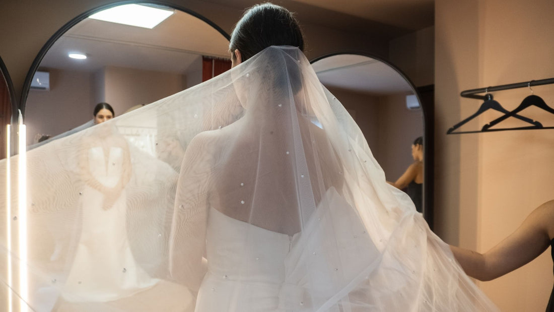 bride posing with her bridal veil and dress in front of mirror