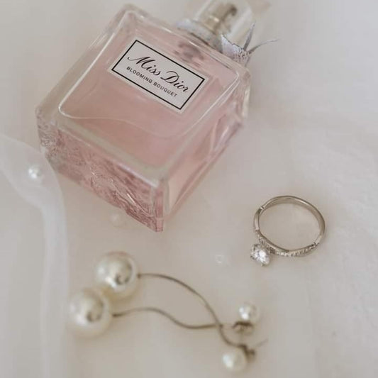 Silver pearl drop bridal earrings and perfume bottle on veil