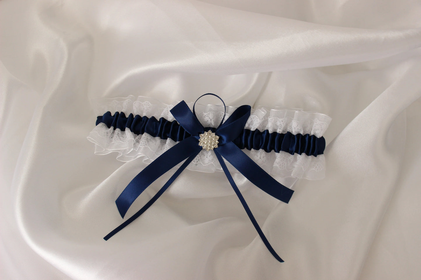 Navy blue and white lace bridal garter on white satin background