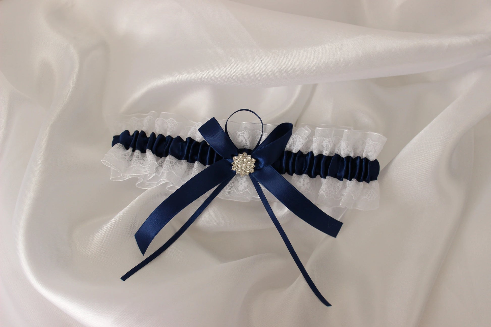 Navy blue and white lace bridal garter on white satin background