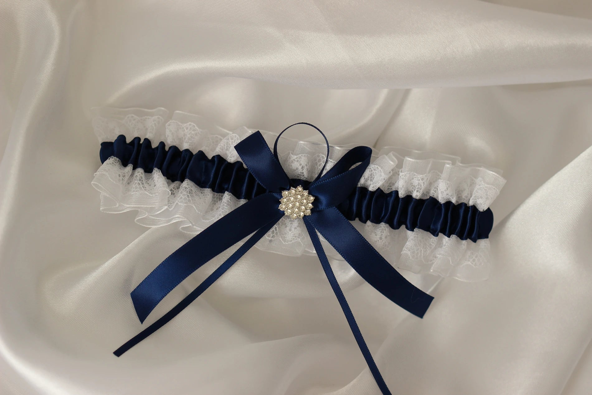 Navy blue lace bridal garter on white satin background