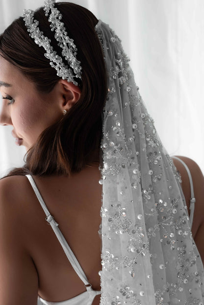 Pearl embellished bridal veil on model in front of white wall