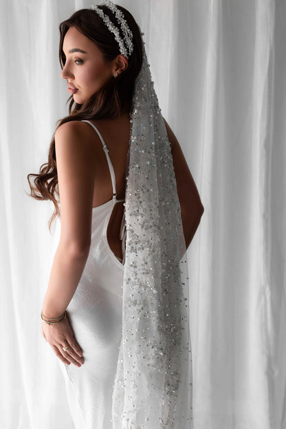 Pearl embellished bridal veil on model in front of white wall