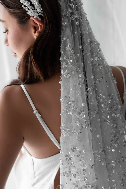 Pearl embellished bridal veil on model in front of white wall