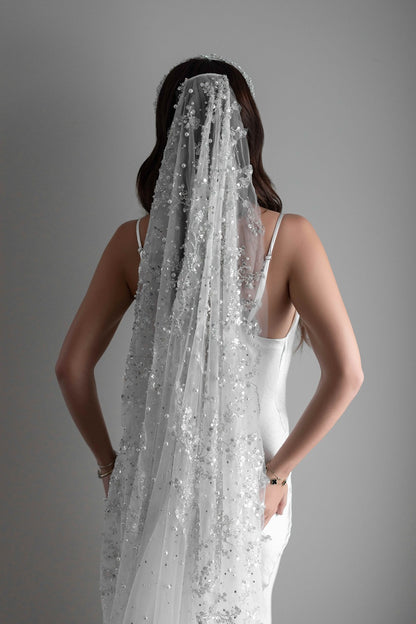 Pearl embellished bridal veil on model in front of white wall
