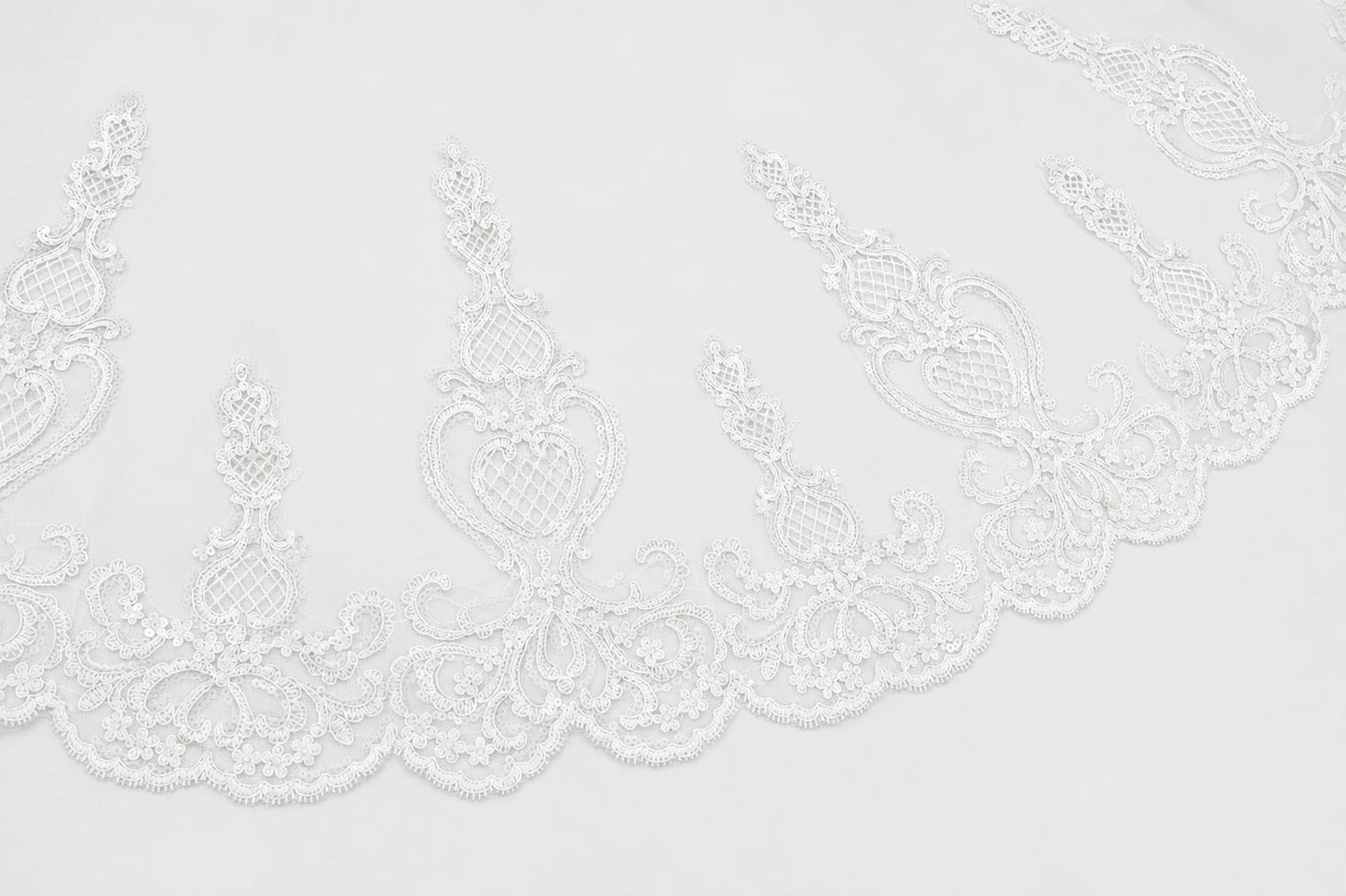 White lace trim with an ornate floral and scroll pattern along a scalloped edge, shown against a plain white background.