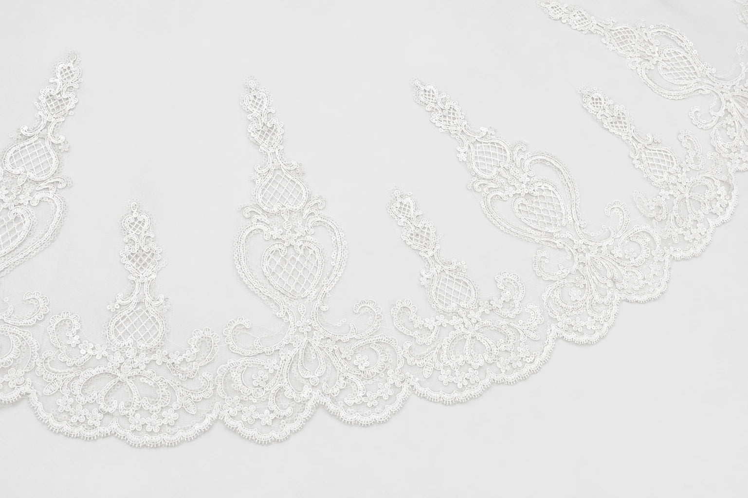 White lace trim with an ornate floral and scroll pattern along a scalloped edge, shown against a plain white background.
