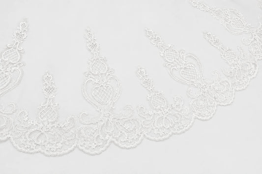 White lace trim with an ornate floral and scroll pattern along a scalloped edge, shown against a plain white background.