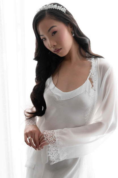 Woman wearing a white lace bridal robe with a tiara on a white background