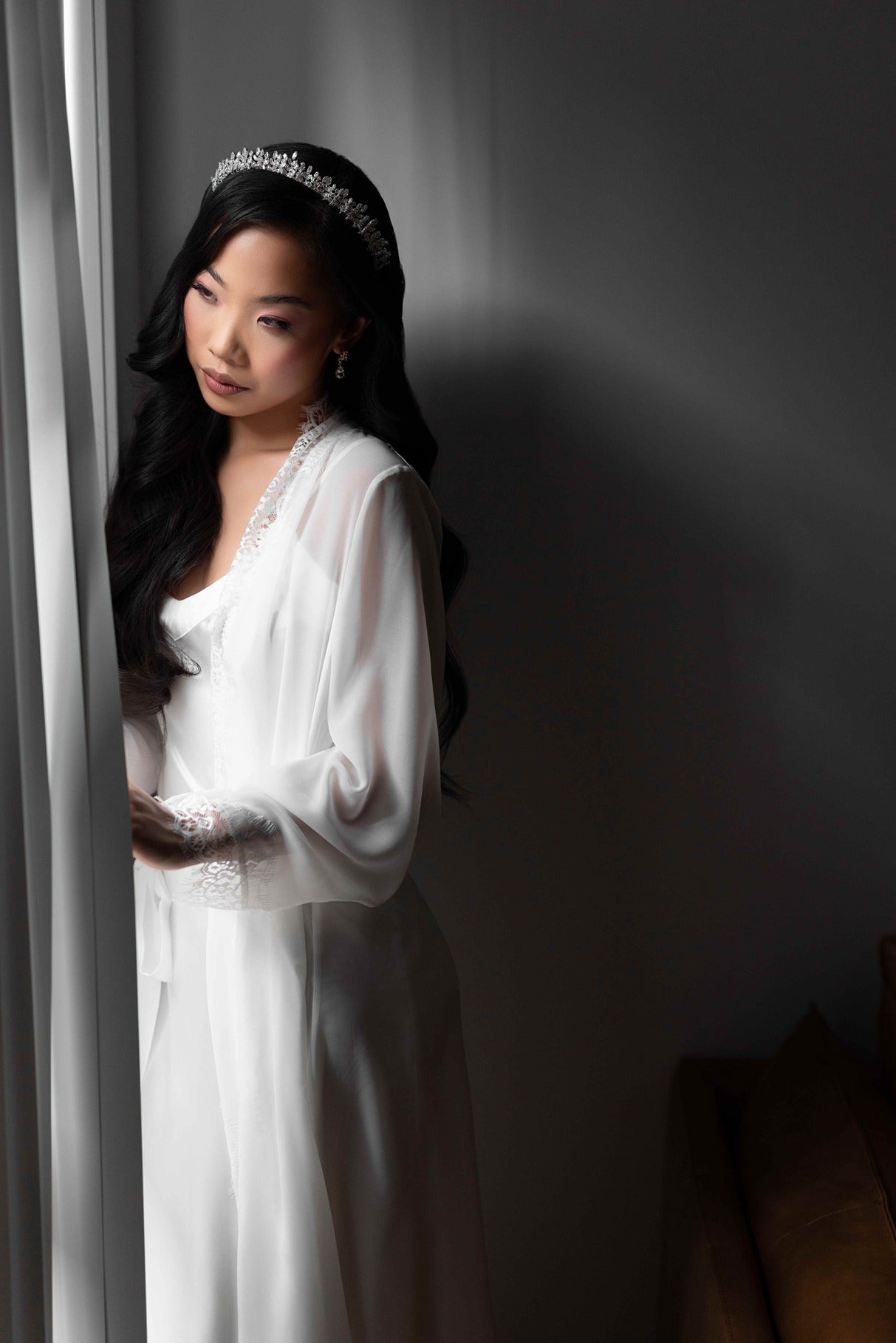 Woman in a bridal robe with a tiara against a dark background