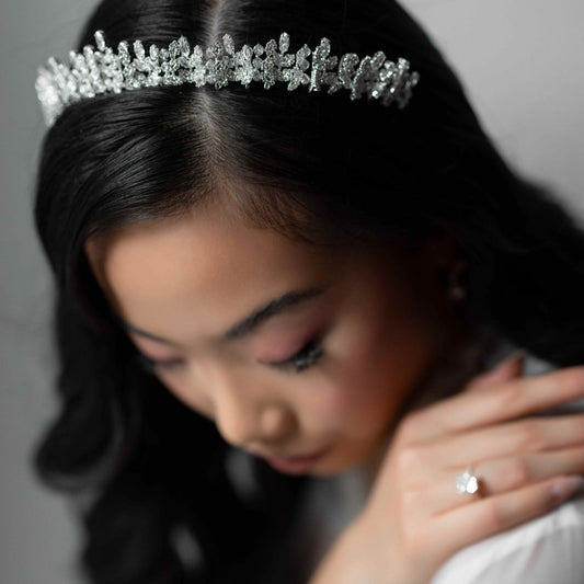 Woman wearing a silver tiara and ring on a gray background