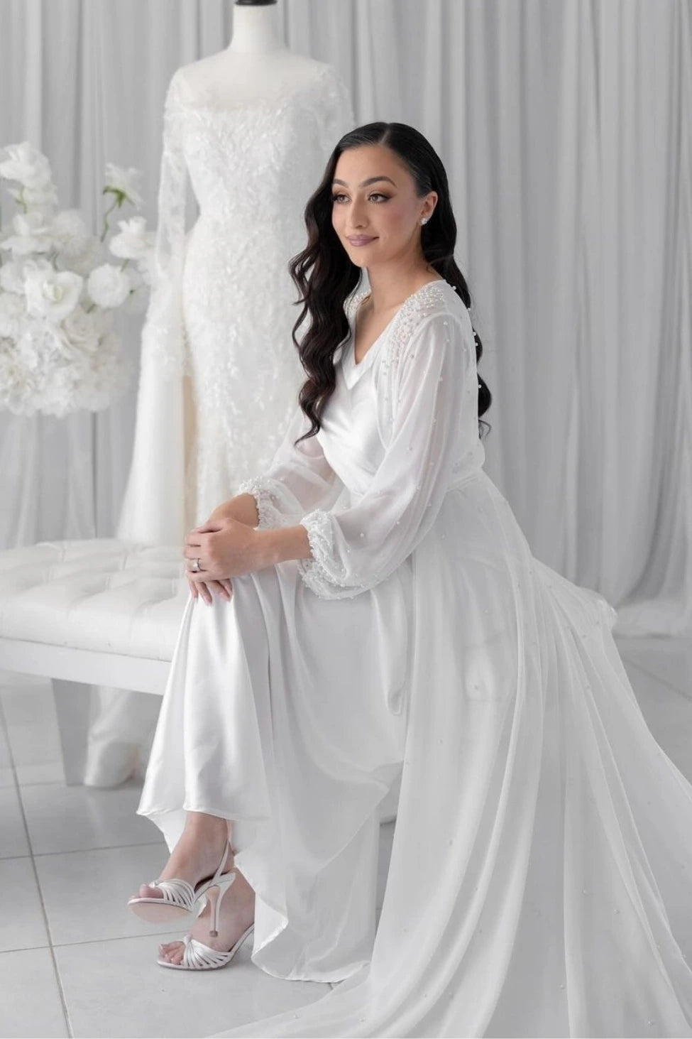 Bride wearing bridal robe and slip next to wedding dress