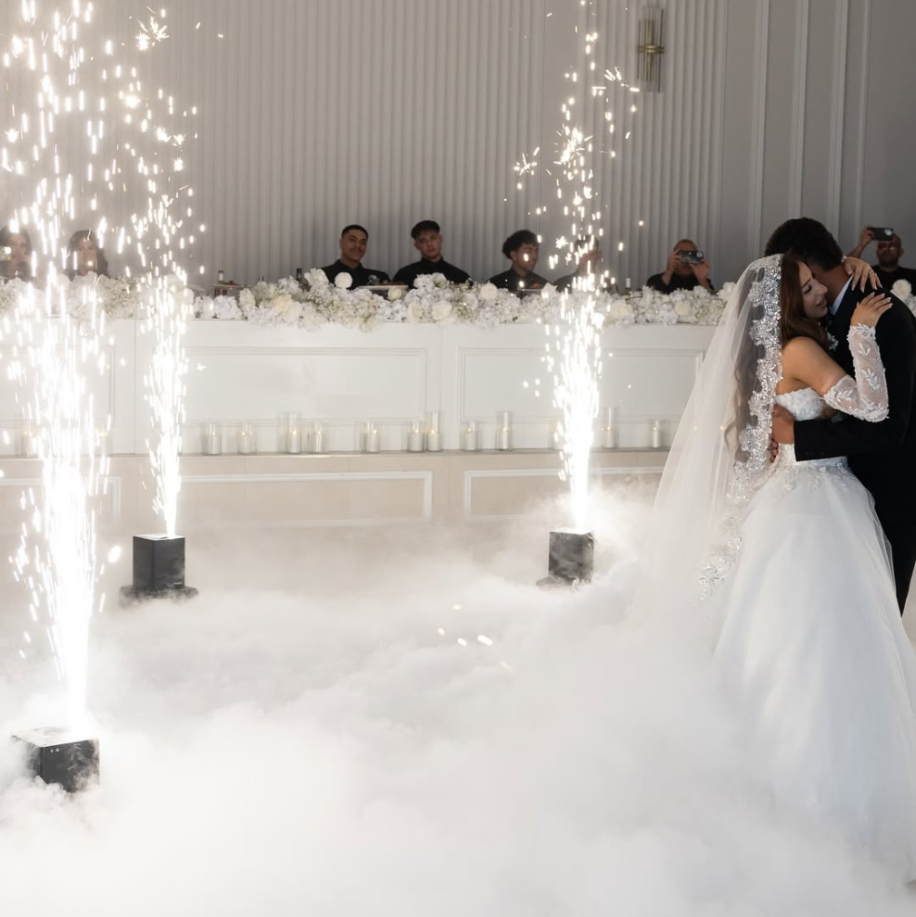 Bride wearing lace mantilla veil next to groom