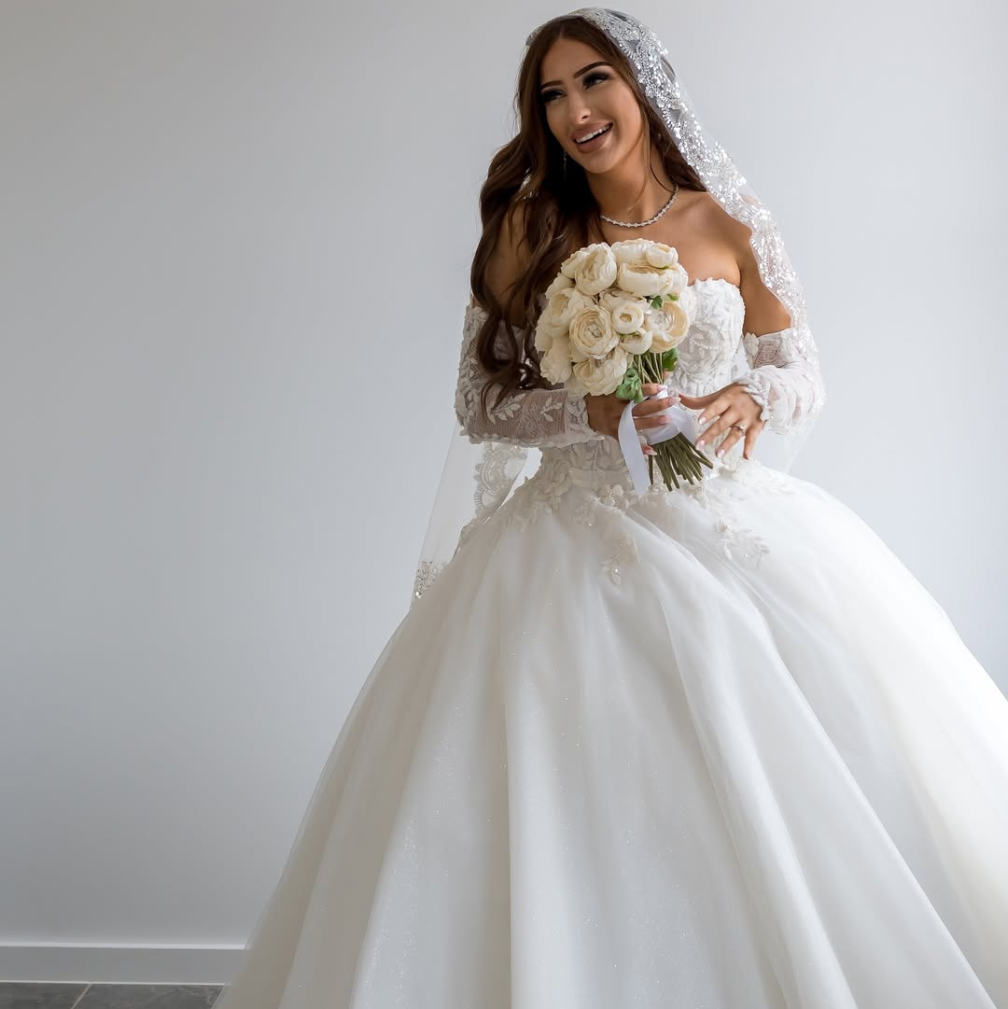 Bride wearing lace mantilla veil against white background