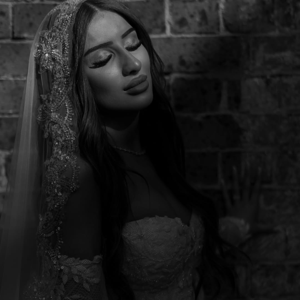 Bride wearing lace mantilla veil against brick wall