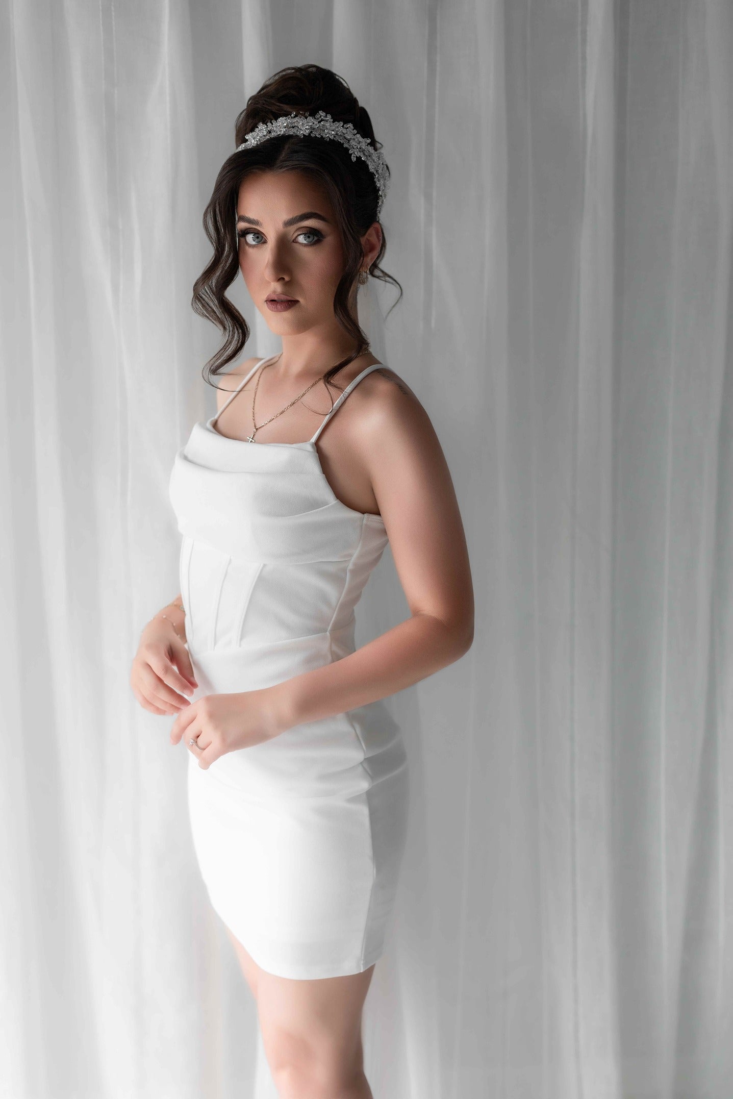 Woman wearing a white bridal slip dress against a plain background