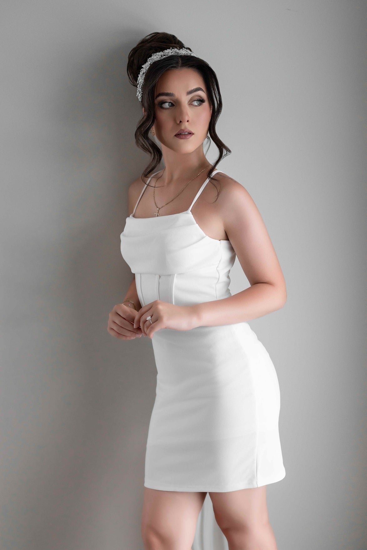 Woman wearing a white bridal slip dress against a plain background