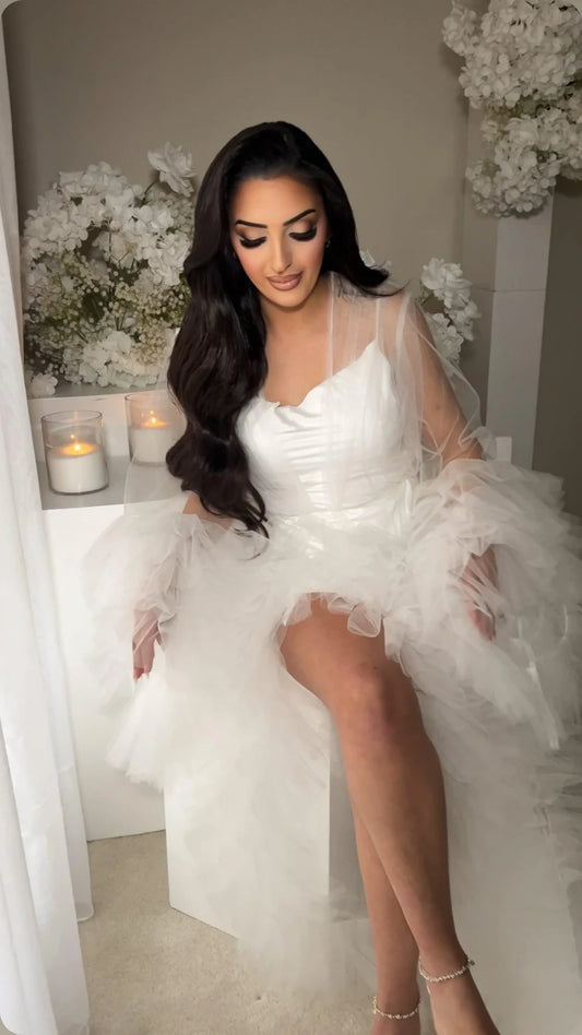 Model wearing bridal slip and fluffy bridal robe in front of white stand with candles