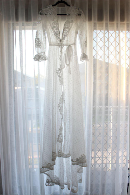 Ariana Lace Robe hanging on a black hanger against a white curtain background