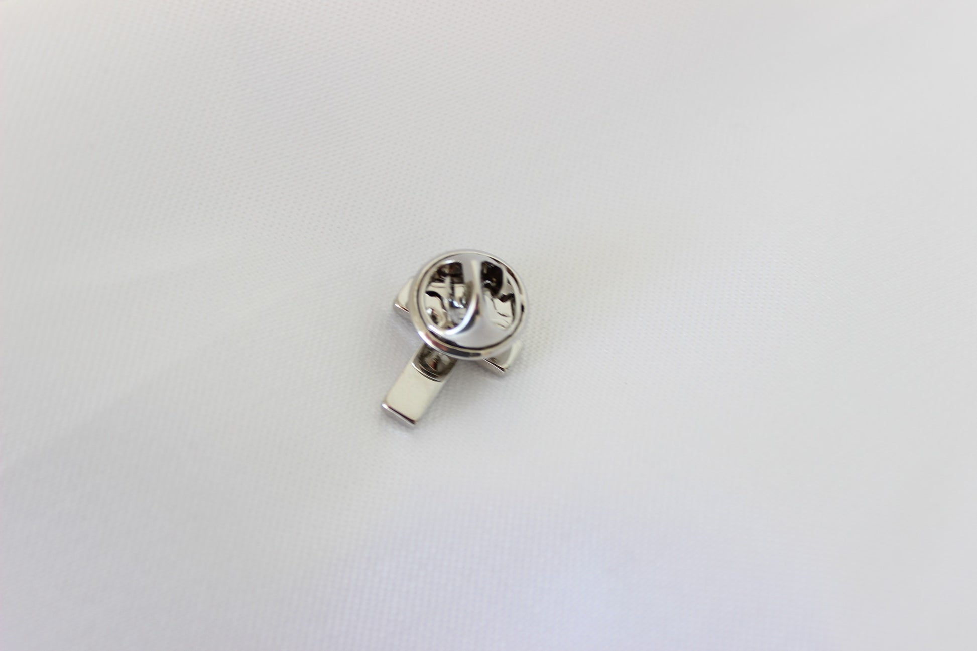 Black and silver cross pin worn on men’s suit lapel