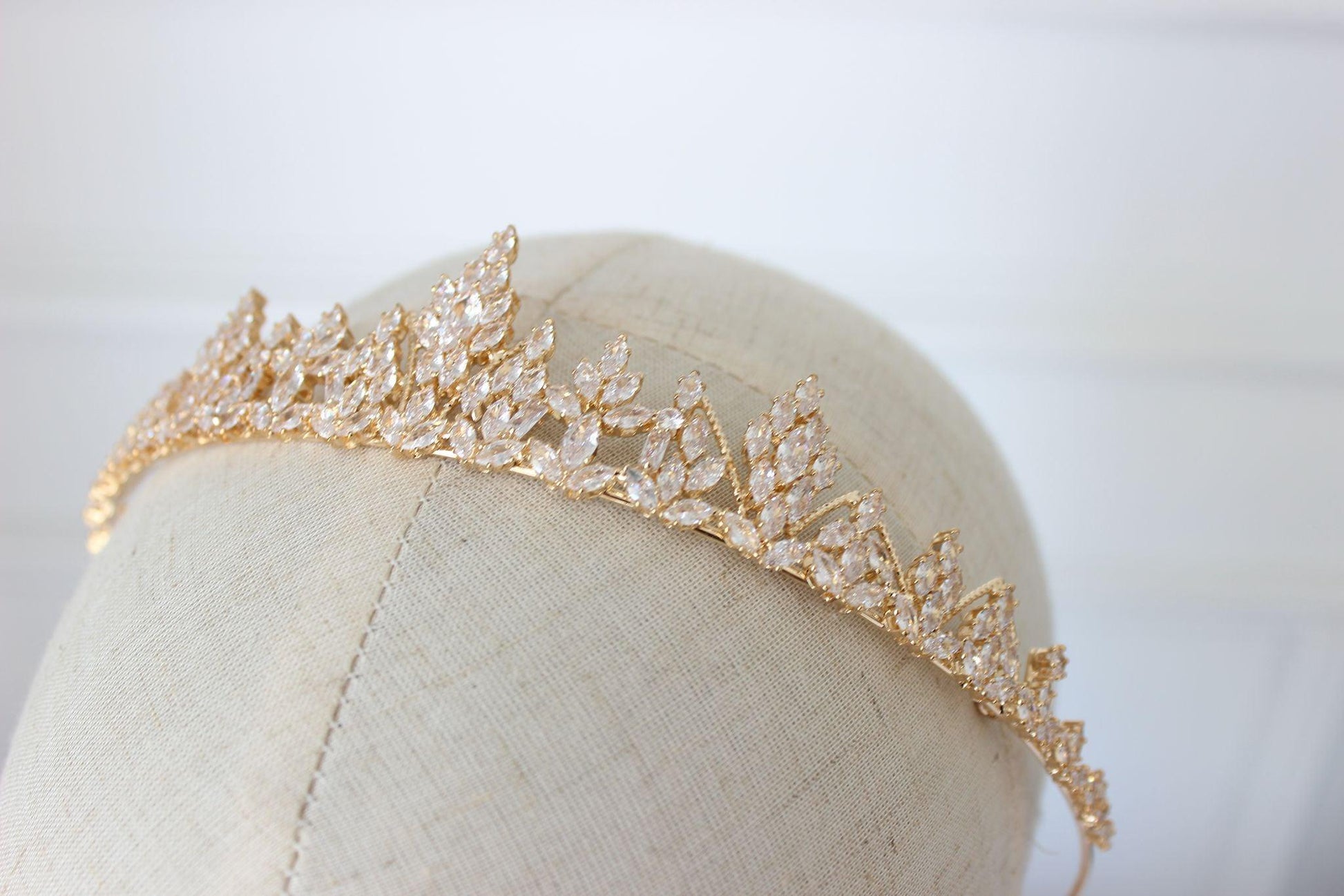 Gold bridal tiara with sparkling cubic zirconia crystals shown on mannequin for bride wedding look