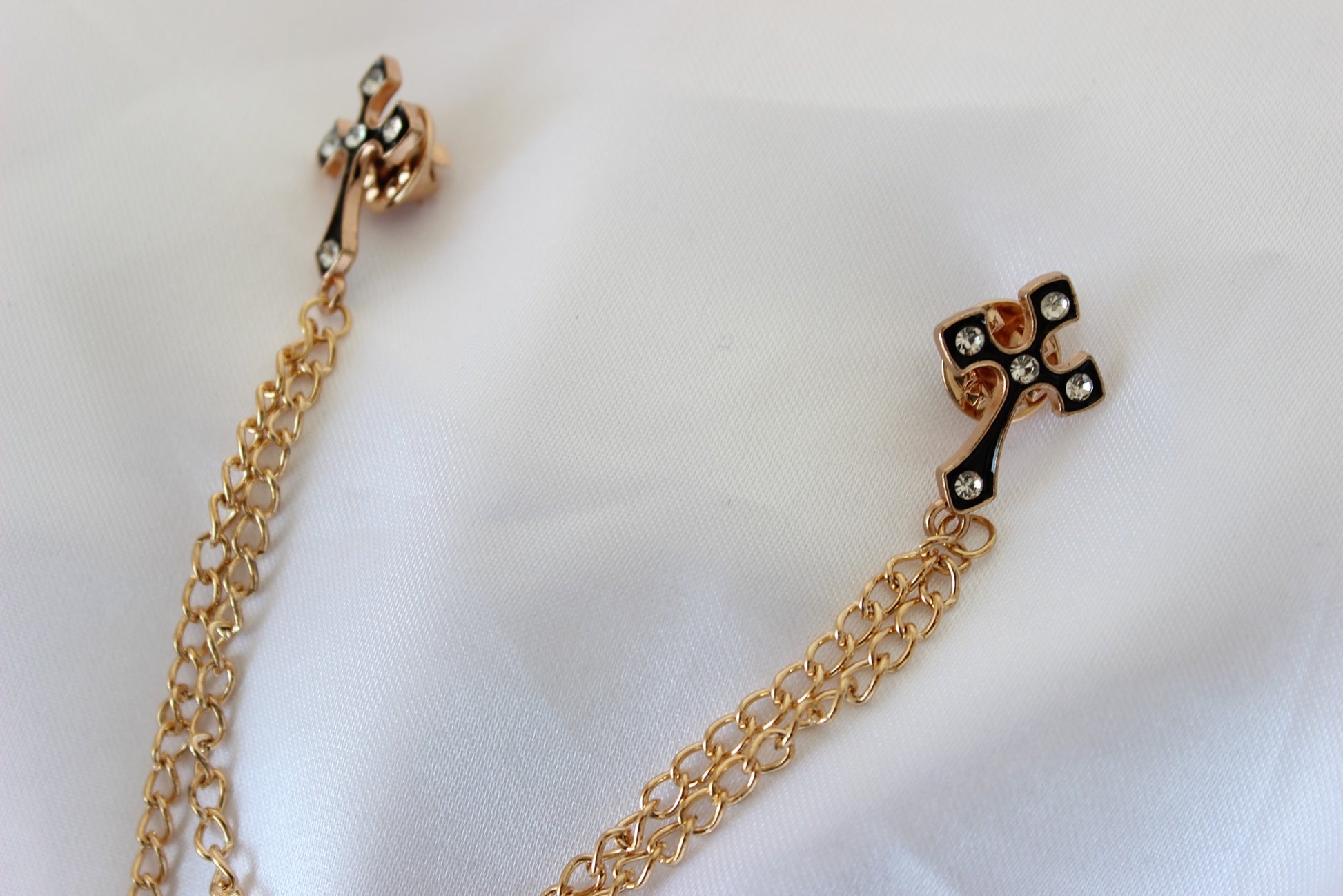 Rose gold cross chain pin worn on suit lapel