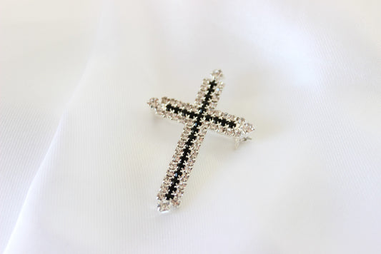 Silver and black cross brooch on white background