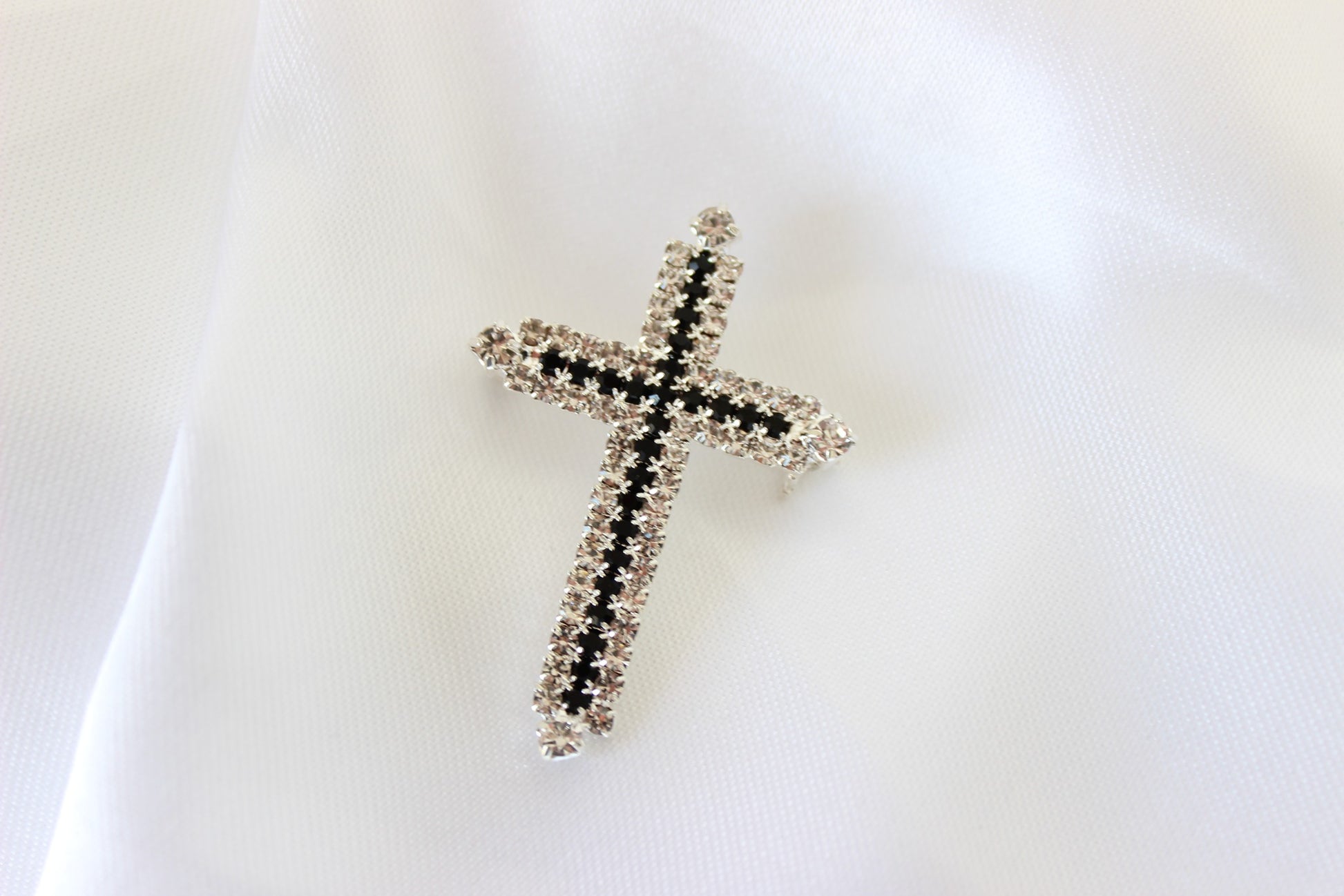 Silver and black cross suit brooch on white background