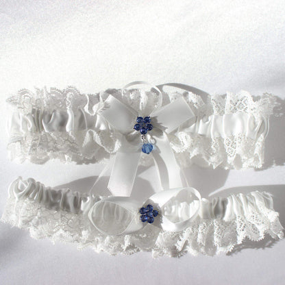 White bridal garter set with lace and central blue flower emblems on white background