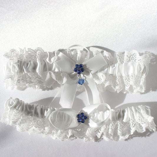 White bridal garter set with lace and central blue flower emblems on white background